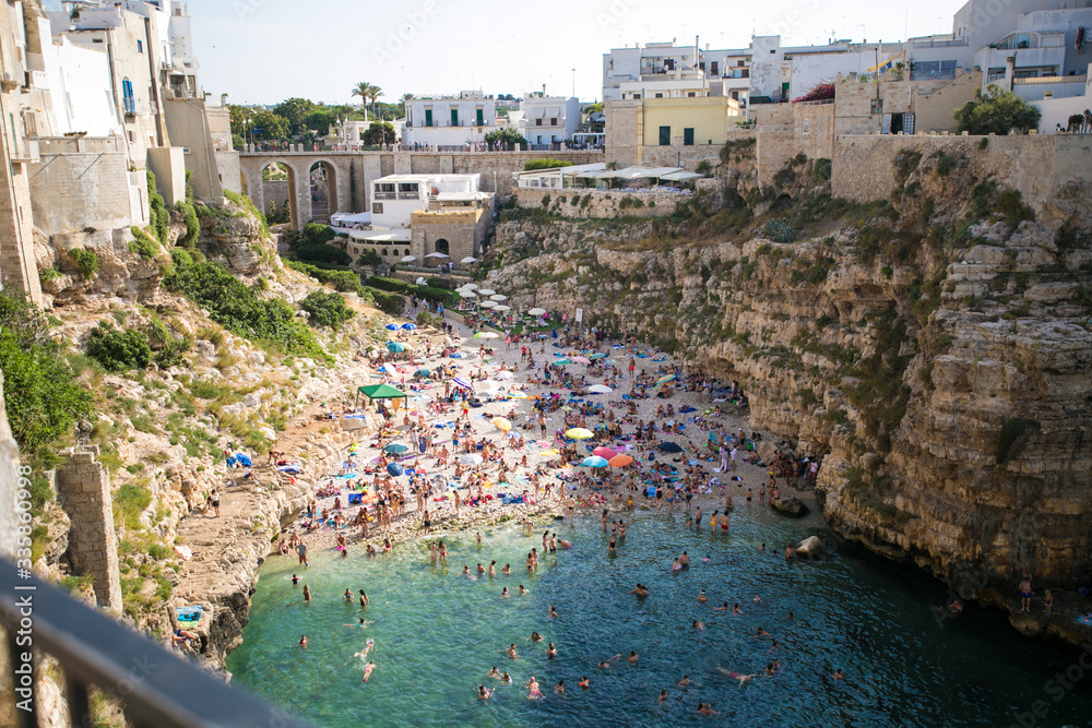 Beautiful beach with people in Polignano a Mare in the southern part of Italy crystal clear azure water