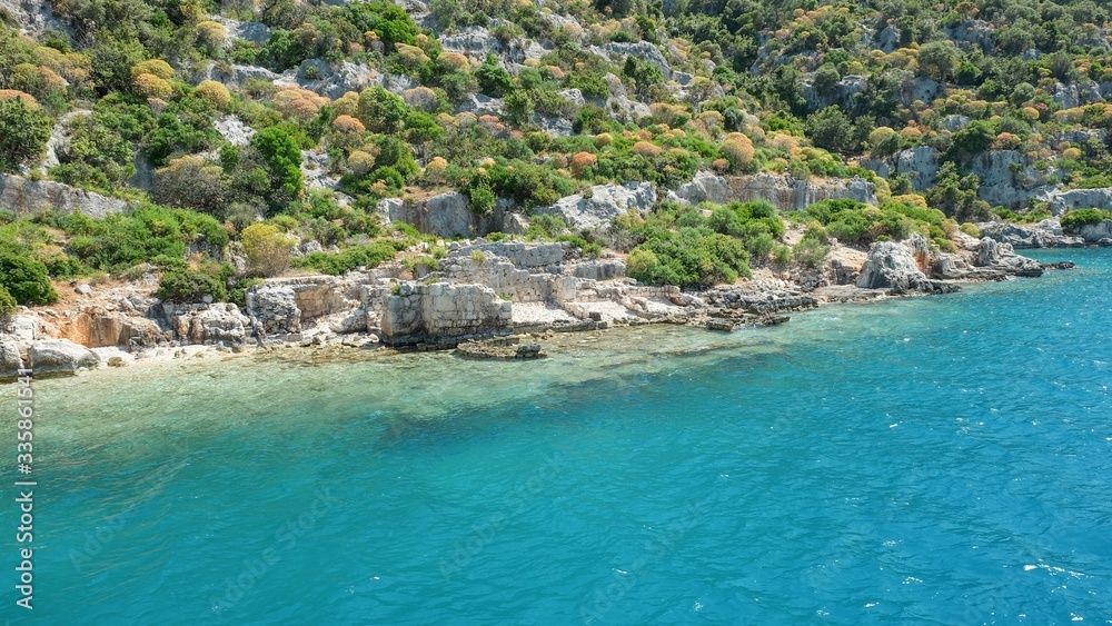 Panoramic view from tourist yacht to weathered ruins of famous ancient underwater town Sunken City on Kekova island, in mediterranean coastline of Antalya province. Popular tourist places in Turkey.