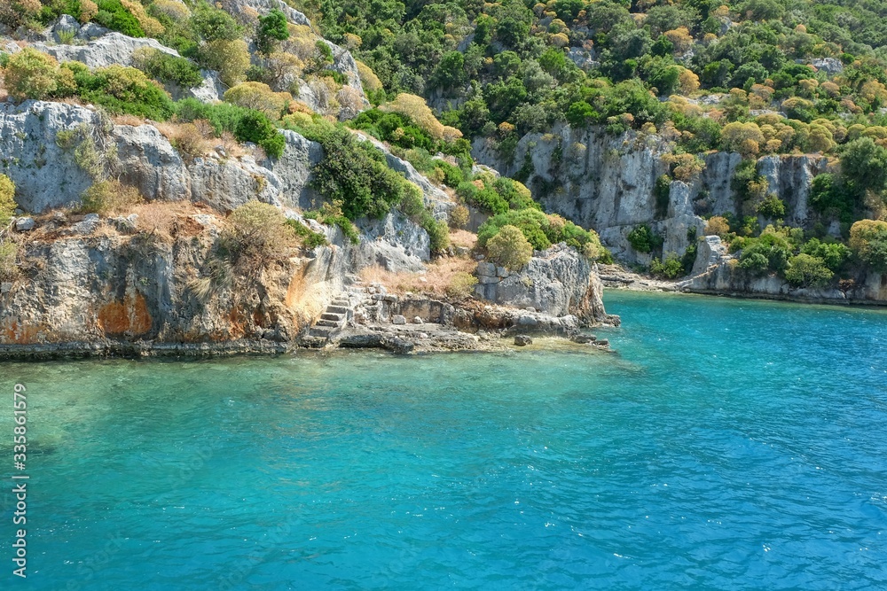 Obraz premium Descending ruined staircase to sea among weathered ruins of famous ancient underwater town Sunken City on Kekova island, in mediterranean coastline of Antalya province,Turkey.
