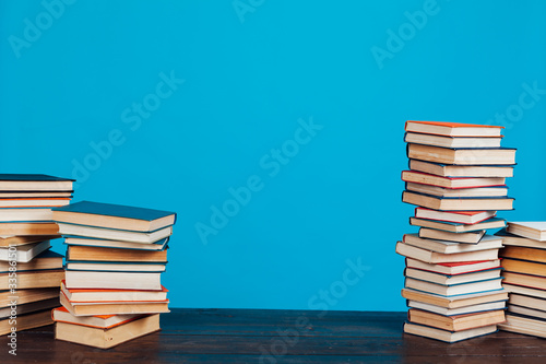 many stacks of educational books for learning preparation for college exams on a blue background