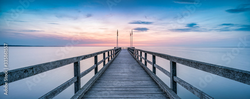 Panoramic view of a wooden pier during sunset at the sea photo