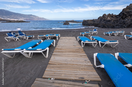 Blue sunbeds and black sand beach at Los Cancajos. La Palma, Canary Island, Spain.