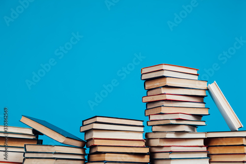 many stacks of educational books for learning preparation for college exams on a blue background
