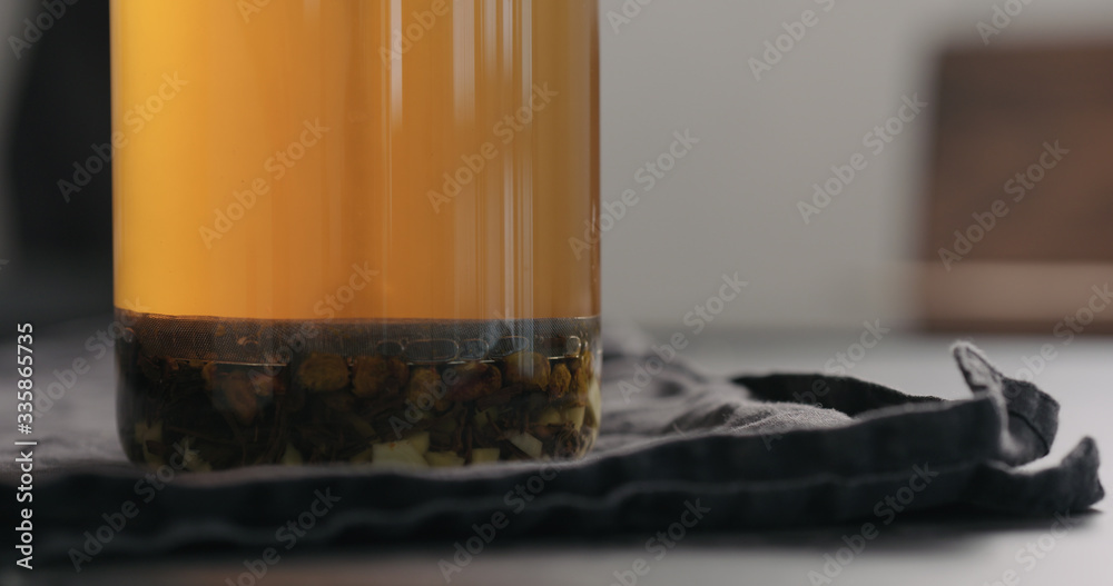 push french press with poured black tea with ginger and seaberry with hot water in glass beaker on kitchen countertop