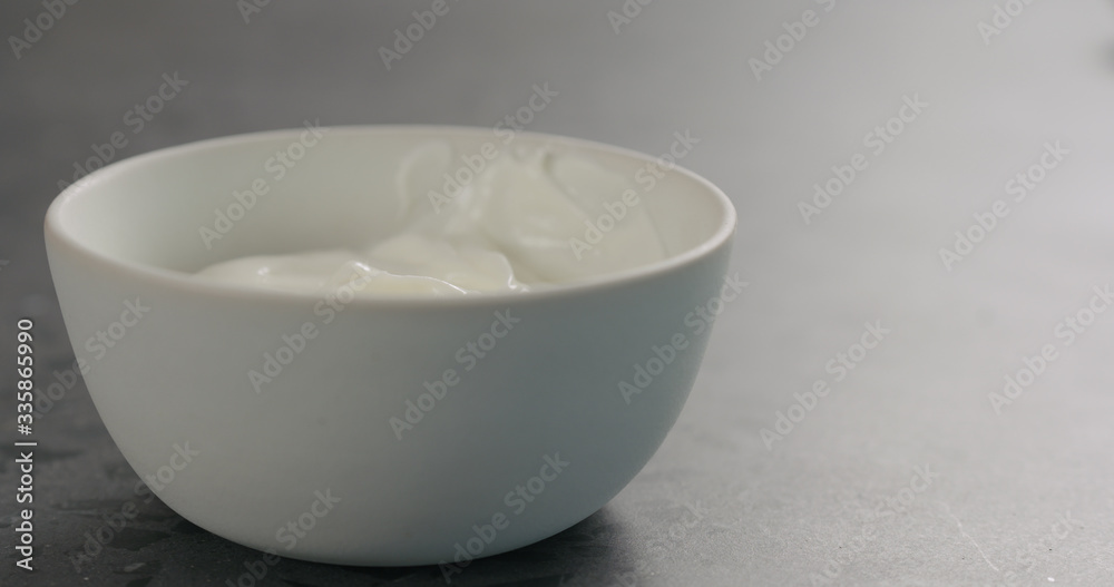 white yogurt in white bowl on concrete surface white yogurt in white bowl on concrete surface