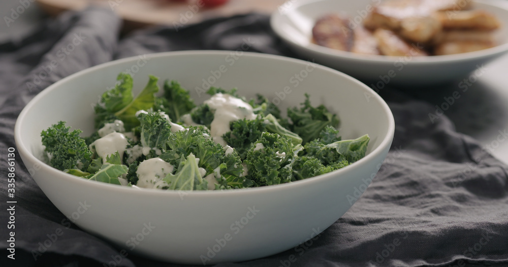 pour caesar dressing on kale leaves in white bowl pour caesar dressing on kale leaves in white bowl