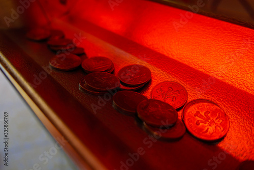 Two pence 2p pieces coins in the tray below a tuppeny nudger machine at a British seaside funfair. photo