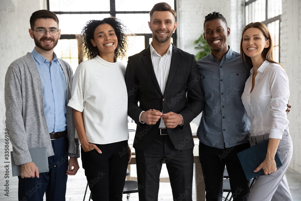 Portrait of standing in row smiling diverse team looking at camera. Happy multiethnic corporate staff, young specialists, company representatives, bank workers photo shoot, HR agency recruitments. Portrait of standing in row smiling diverse team looking at camera. Happy multiethnic corporate staff, young specialists, company representatives, bank workers photo shoot, HR agency recruitments.