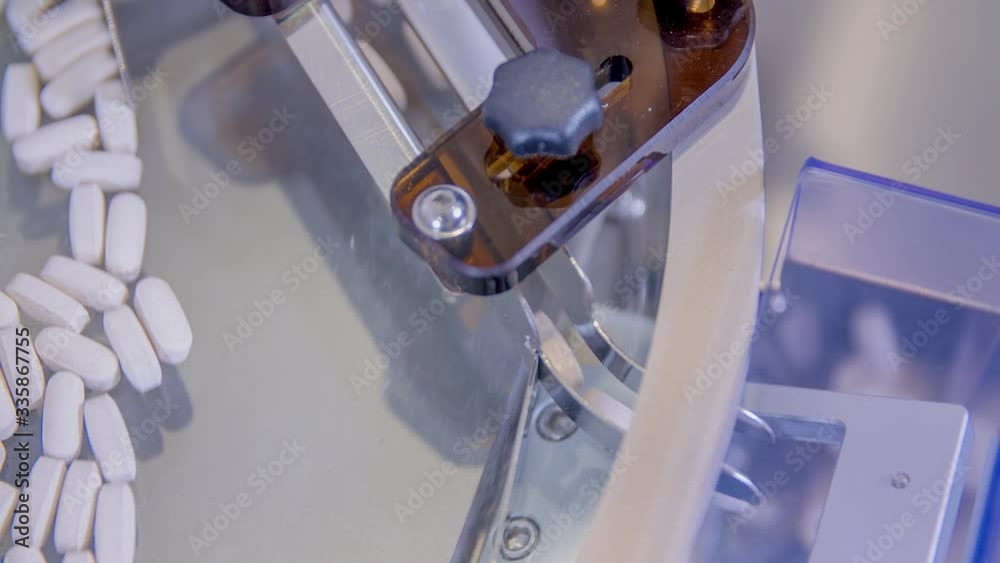 Close up of white pills spinning on a bottling machine in a pharmaceutical lab
