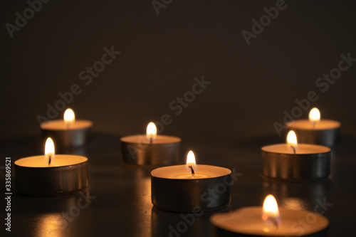 Seven small lighted candles in the dark, selective focus of the candlelight
