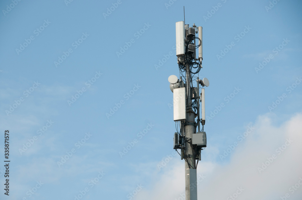 Cell tower closeup against a white sky.