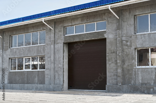construction or renovation of a single-story building with a large gate, such as a garage or repair shop, windows and gray plaster