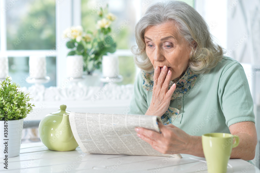 Close up portrait of senior woman reading newspaper Close up portrait of senior woman reading newspaper