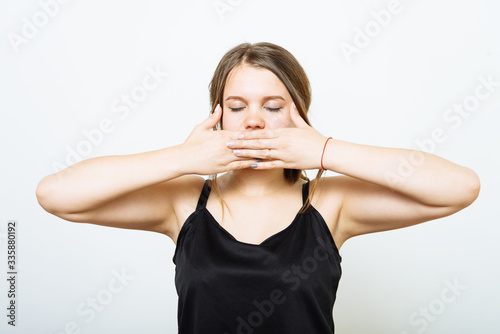 Successful stylish girl covers her mouth with her hands, isolated in the studio