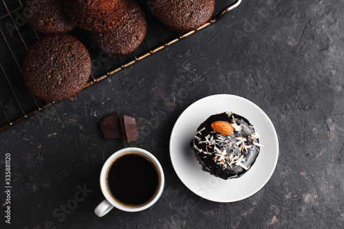 Chocolate cupcakes, muffins with banana, nuts and a Cup of coffee. On a black table and a dark background. Top view, side view. Close-up and medium plan. Space for text.