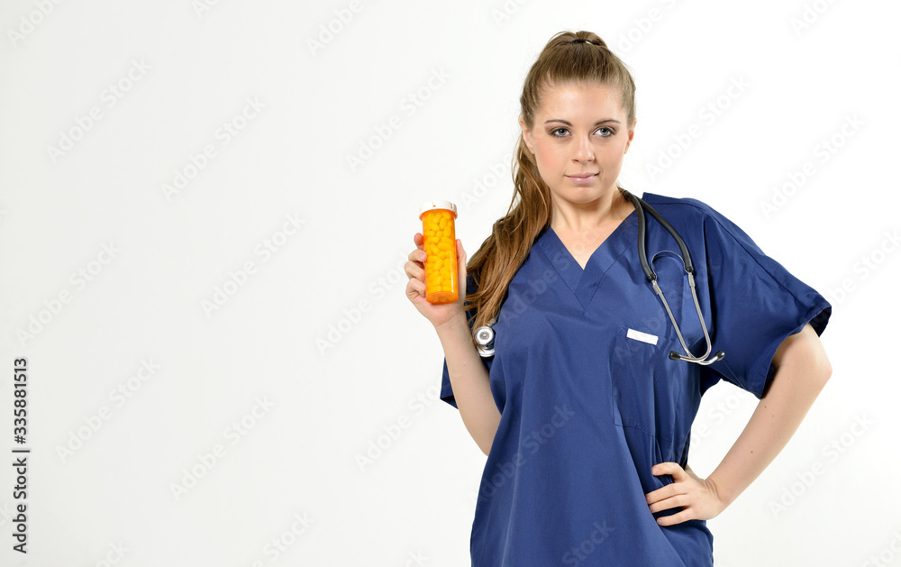 Beautiful young female medical professional with stethoscope smiling as she holds a bottle of pills - studio - no PPE present Beautiful young female medical professional with stethoscope smiling as she holds a bottle of pills - studio - no PPE present