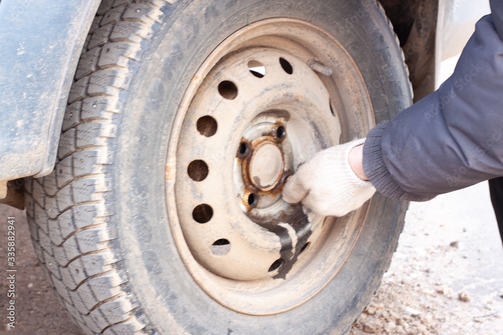 a man unscrews the bolts on the wheel of a car. wheel replacement a man unscrews the bolts on the wheel of a car. wheel replacement