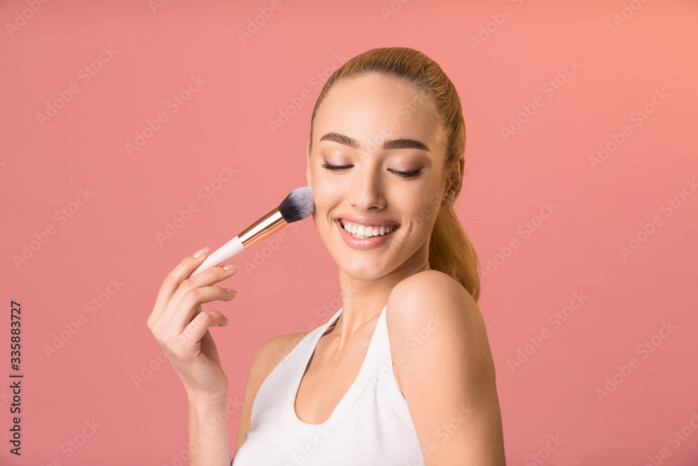 Girl Using Make-Up Brush Applying Face Powder Over Pink Background Girl Using Make-Up Brush Applying Face Powder Over Pink Background