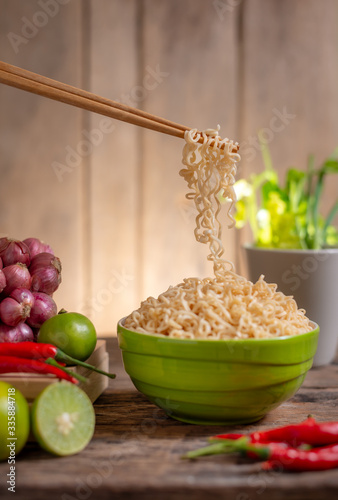 Noodle in a bowlwith lime and chili and onion and vegetable on wooden table photo