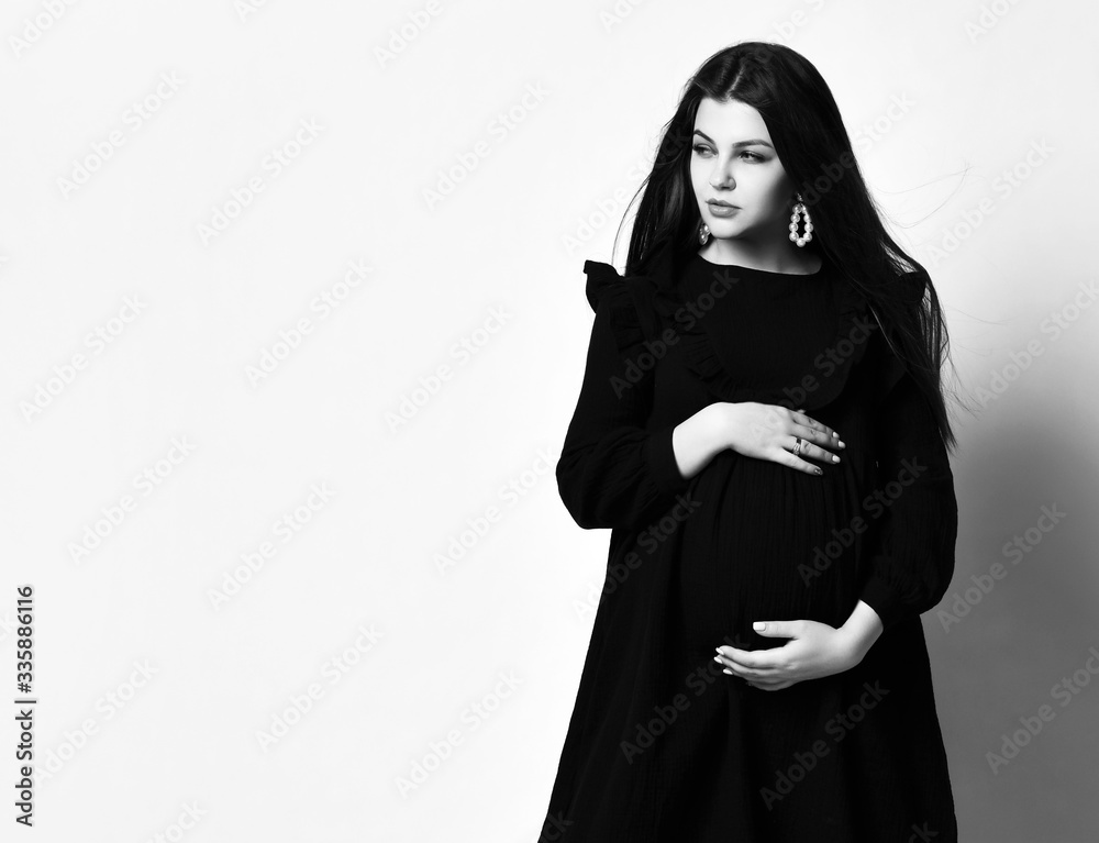 Young beautiful slim pregnant woman with long hair in black long dress. Pregnancy fashion look concept