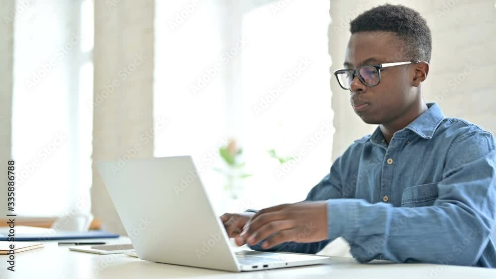 Young African Man Coming Back and Working on Laptop in Office Young African Man Coming Back and Working on Laptop in Office