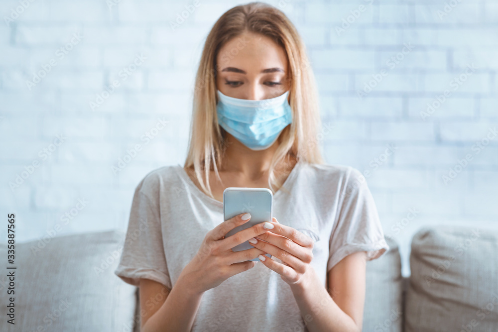 Woman in protective mask typing on smartphone Woman in protective mask typing on smartphone