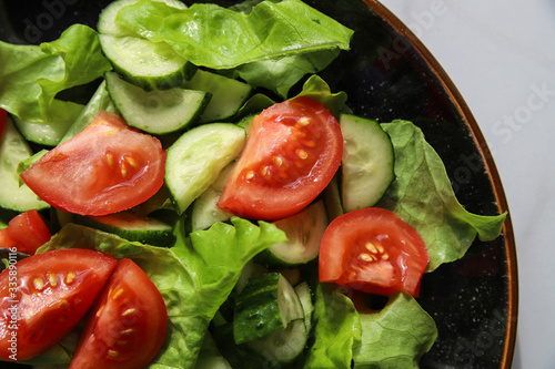 Fresh summer vegetable salad with tomatoes, cucumber, lettuce and olive oil. Healthy food for vegetarian or vegan