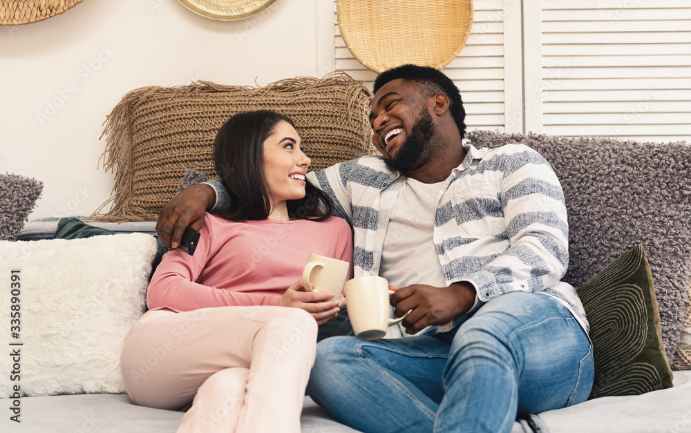 Man and woman sit on sofa and laugh