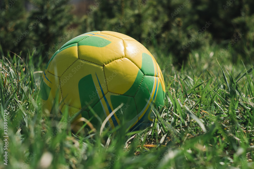 Fototapeta premium yellow ball lying on the green grass, soccer ball, football