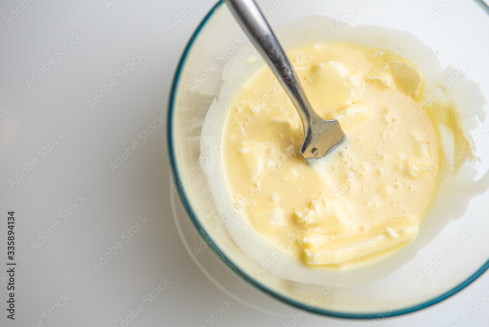 butter soda flour and sour cream are mixed in a transparent bowl on a white background. cream for anthill cake. butter soda flour and sour cream are mixed in a transparent bowl on a white background. cream for anthill cake.
