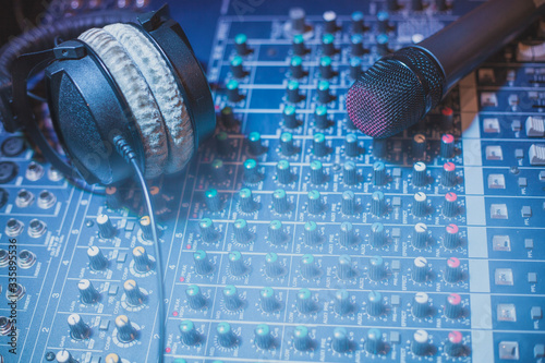 Microphone and headphones resting on an audio mixer and disco light with space to edit a poster or flyer of a party or event. photo