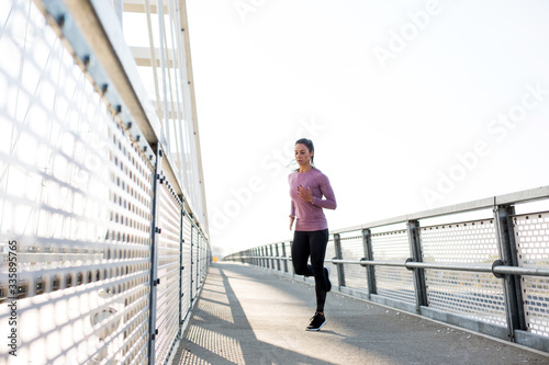 Beautiful fit woman in good shape jogging alone on city bridge. © Sanja