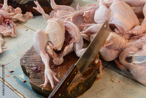 Large cleaver on a wooden chopping board with a number of chicken carcasses at a Thai butchers, Thailand photo