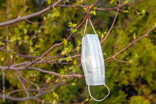 Protective medical mask on the branches of spring trees. Coronavirus quarantine concept.