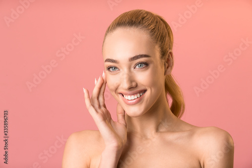 Smiling Lady Applying Facial Cream Looking Aside Posing In Studio