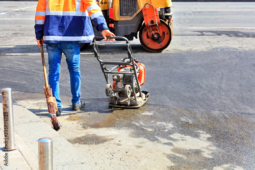 A road worker uses a gasoline vibratory compactor, a vibratory roller and an old broom to repair the road.