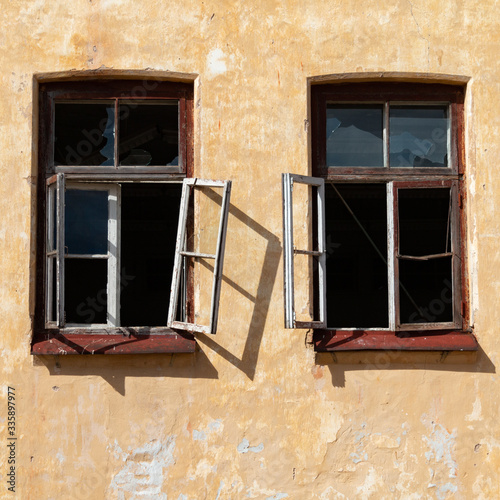 Broken open windows in an old house in sunny weather