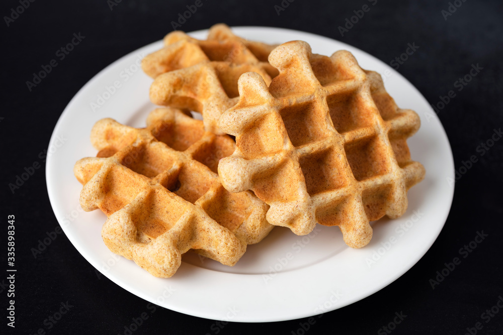Homemade belgian waffles on plate, isolated on black background. Breakfast food sweet golden crunchy waffles Homemade belgian waffles on plate, isolated on black background. Breakfast food sweet golden crunchy waffles