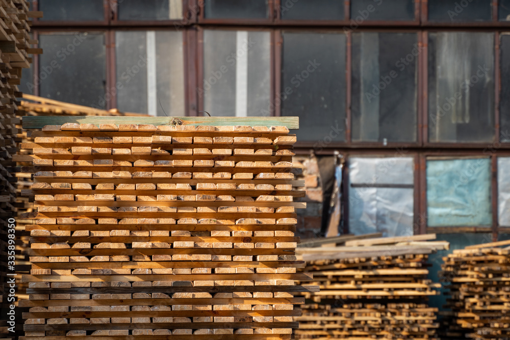 Warehouse for sawing boards on a sawmill outdoors. Timber mill, sawmill. Storage of planed wooden boards. Piles of wooden boards in the sawmill. Planking. Industry. Warehouse for sawing boards on a sawmill outdoors. Timber mill, sawmill. Storage of planed wooden boards. Piles of wooden boards in the sawmill. Planking. Industry.