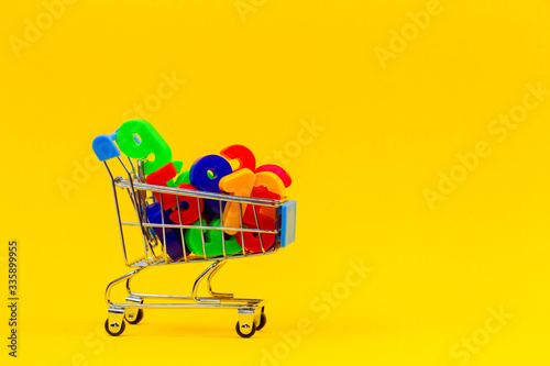 Mini shopping cart or supermarket trolley full of colorful numbers on yellow background