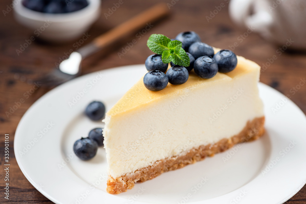 Cheesecake with blueberries on white plate. Classical New York cheesecake. Wooden background Cheesecake with blueberries on white plate. Classical New York cheesecake. Wooden background