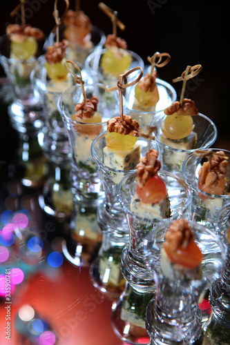 heese canapes with grapes and walnuts on the festive table. Catering services for events. Photo on a dark background.