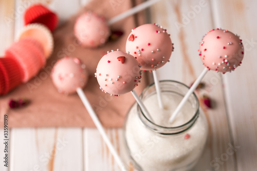 Dessert on a stick. Pink cake pops with a sprinkle on a wooden background. photo