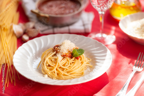 Piatto di spaghetti con sugo rosso, parmigiano grattugiato e basilico