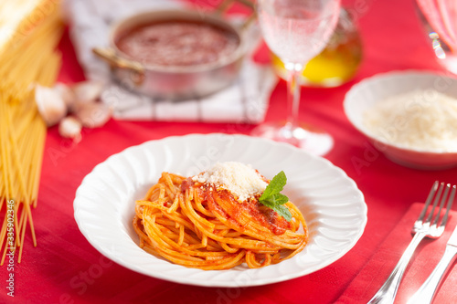 
Spaghetti cotti conditi con la salsa di pomodoro, parmigiano grattugiato e basilico nel piatto
 photo