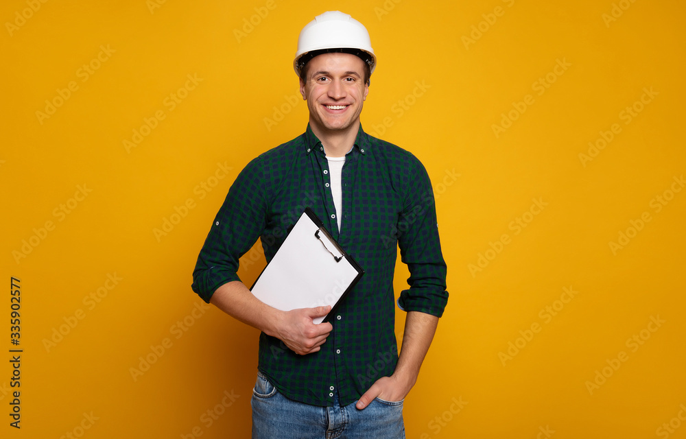 Close up photo of young happy and confident foreman or architect in build helmet is posing isolated on yellow background. Close up photo of young happy and confident foreman or architect in build helmet is posing isolated on yellow background.