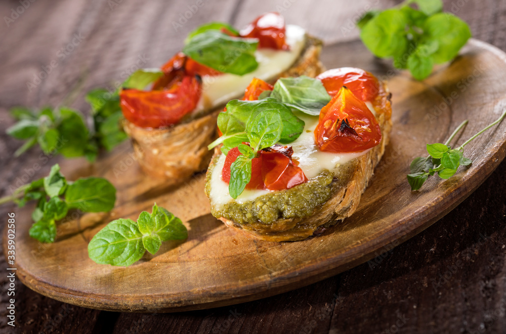 Bruschetta with tomatoes, mozzarella cheese, pesto and fresh basil on wooden background. Bruschetta with tomatoes, mozzarella cheese, pesto and fresh basil on wooden background.
