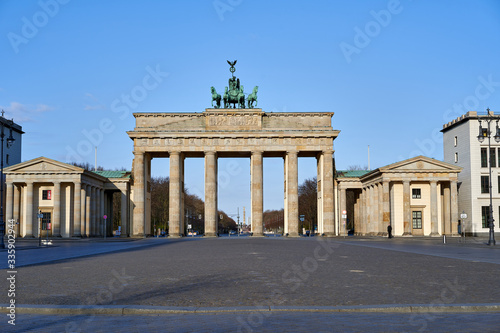 view on the famous Brandenburg gate on the Pariser square in Berlin city, parisian square without tourists and visitors - deserted, blue sky, small clouds