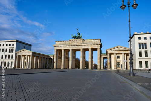 view on the famous Brandenburg gate on the Pariser square in Berlin city  parisian square without tourists and visitors - deserted  blue sky  small clouds