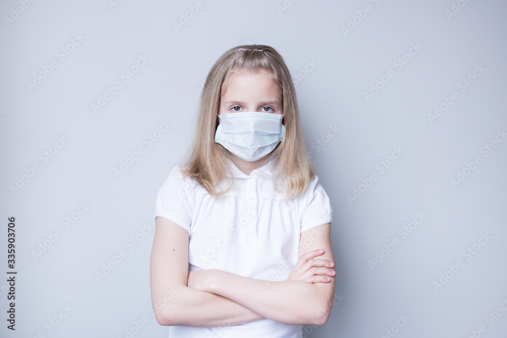 Schoolgirl with a mask on her face. Emotion, sad. Grey background. Schoolgirl with a mask on her face. Emotion, sad. Grey background.